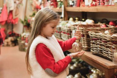 Bir kız Noel ağacı için oyuncakları seçer.