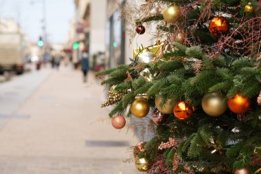 Şehirdeki dükkanların yakınında altın toplarla süslenmiş Noel ağaçları.