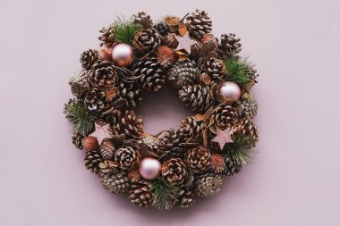 Dallı Noel çelengi ve pembe arka planda altın toplar.