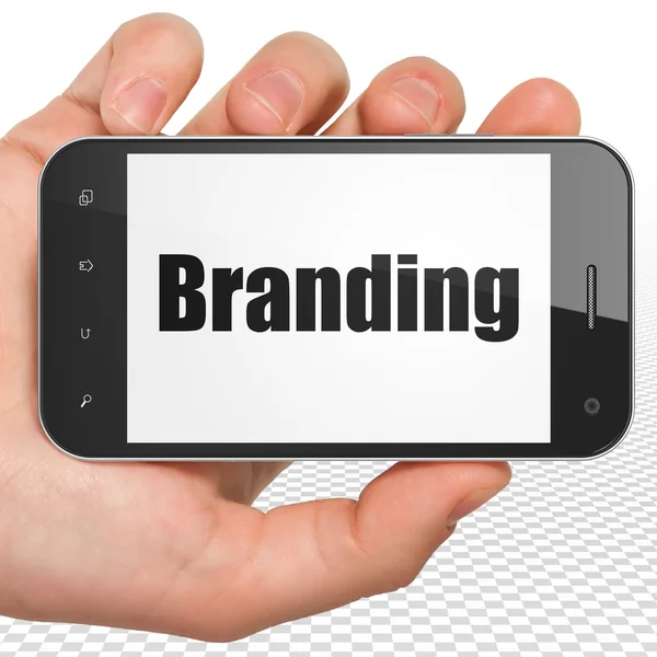 Marketingové koncepce: ruka držící Smartphone s Branding na displeji — Stock fotografie