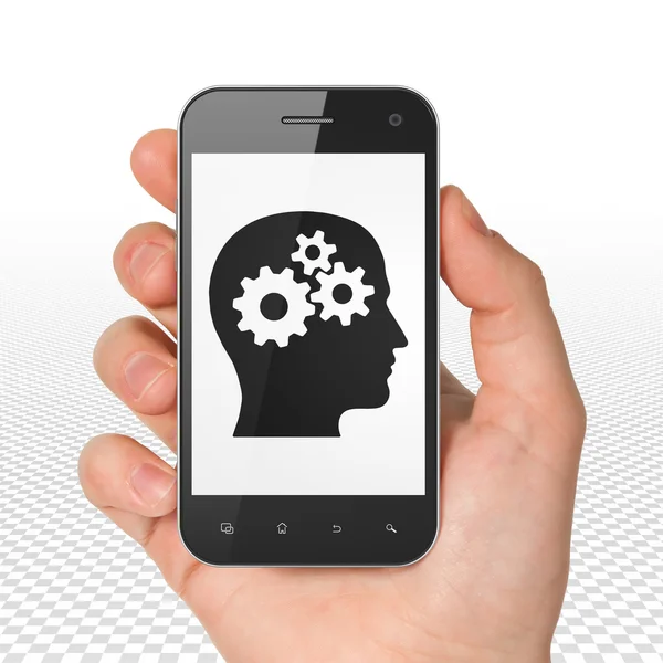 Affärsidé: hand hålla smartphone med huvud med kugghjul på displayen — Stockfoto