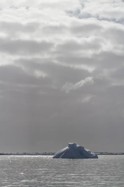 Ijsberg in de Oceaan, backlit op een bewolkte bewolkte dag — Stockfoto