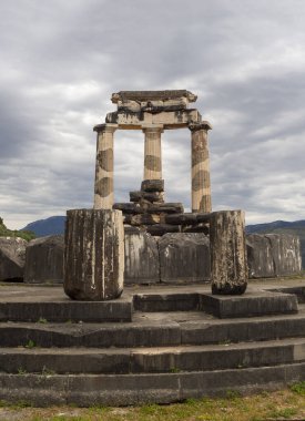Yunanistan 'ın Delphi kentindeki dağların arasında fırtınalı bir gökyüzüne karşı Athena Pronaia Tapınağı' nın panoramik manzarası