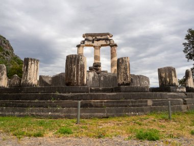 Yunanistan 'ın Delphi kentindeki dağların arasında fırtınalı bir gökyüzüne karşı Athena Pronaia Tapınağı' nın panoramik manzarası