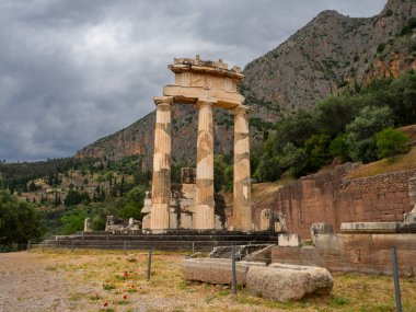 Yunanistan 'ın Delphi kentindeki dağların arasında fırtınalı bir gökyüzüne karşı Athena Pronaia Tapınağı' nın panoramik manzarası