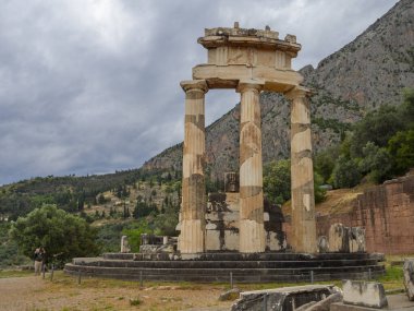 Yunanistan 'ın Delphi kentindeki dağların arasında fırtınalı bir gökyüzüne karşı Athena Pronaia Tapınağı' nın panoramik manzarası