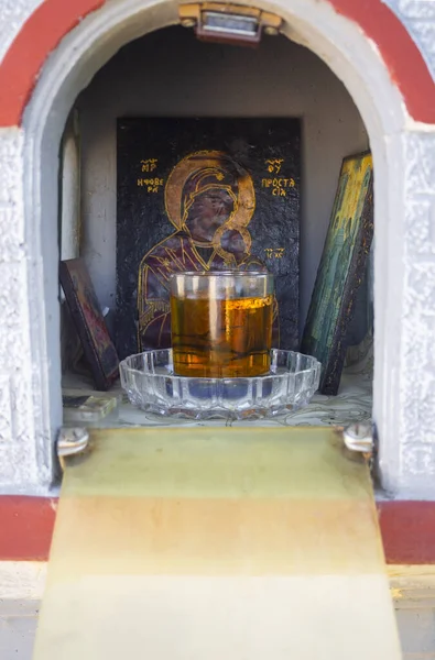 Candelakia - traditional miniature Church by the road in the forest with a burning candle and icons inside on island Evia in Greece