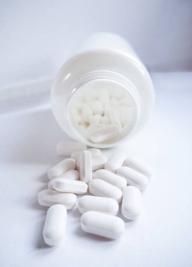 Beyaz ilaç hapları yakın plan beyaz şişe konteynırından yayılmış.