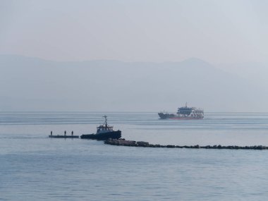 Korfu, Yunanistan. 30 Ekim 2025: Yunanistan 'daki Korfu adasında bir römorkör içinde işçilerle birlikte bir sal sürüklüyor