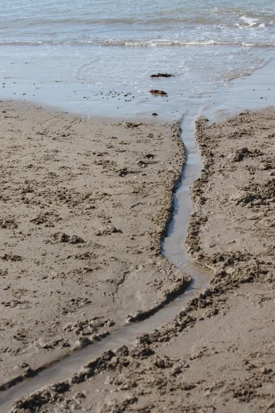 砂浜を渡って流れる水の流れ — ストック写真