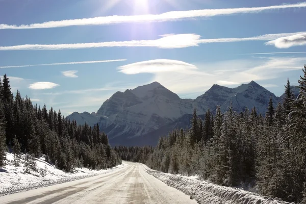 Strada ghiacciata di fronte a una montagna sotto il cielo blu — Foto Stock