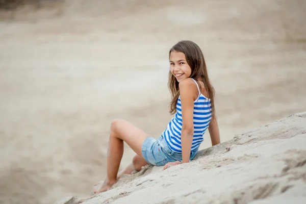 Menina em um colete listrado na areia — Fotografia de Stock