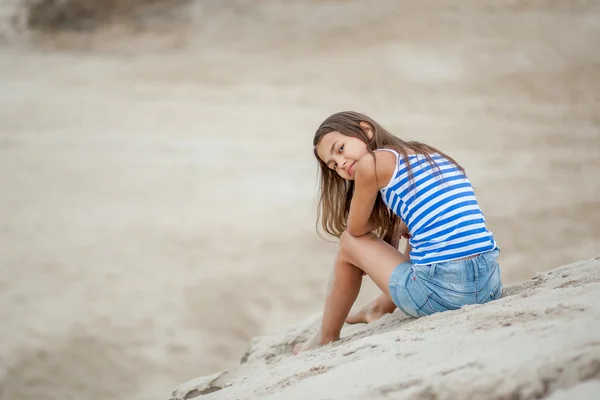Menina em um colete listrado na areia Fotos De Bancos De Imagens