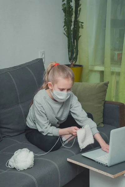 Kız örgü örmeyi, dizüstü bilgisayarda video izlemeyi öğreniyor.