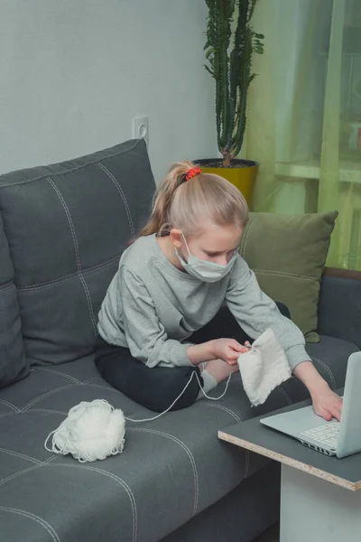 Kız örgü örmeyi, dizüstü bilgisayarda video izlemeyi öğreniyor.