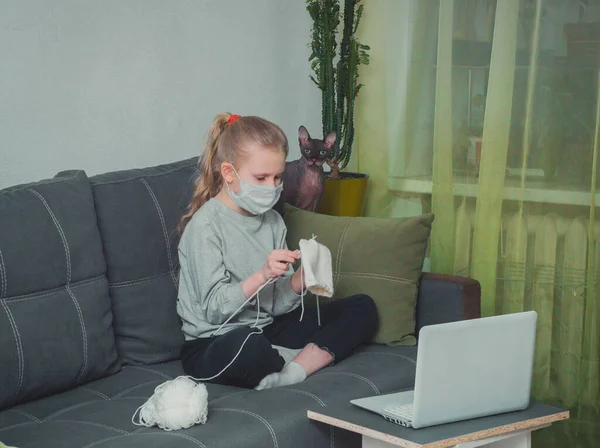 Kız örgü örmeyi, dizüstü bilgisayarda video izlemeyi öğreniyor.