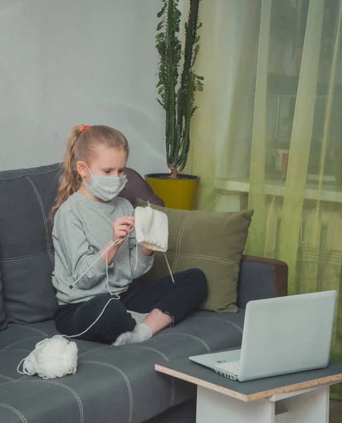 Kız örgü örmeyi, dizüstü bilgisayarda video izlemeyi öğreniyor.