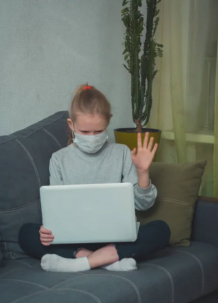 Maskeli kız karantinada dizüstü bilgisayardan video dersleri izliyor.