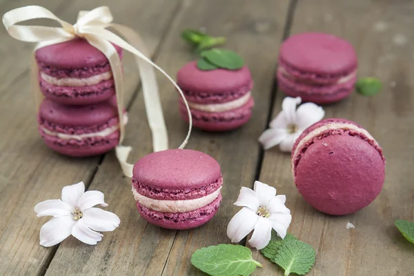 Sweet crimson french macaroons wiht hyacinth flowers and mint on dark wooden background — Stock Photo, Image