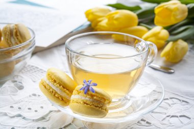 Bir fincan çay, hafif bir arka plan üzerinde sketchbook ve limon macaroons