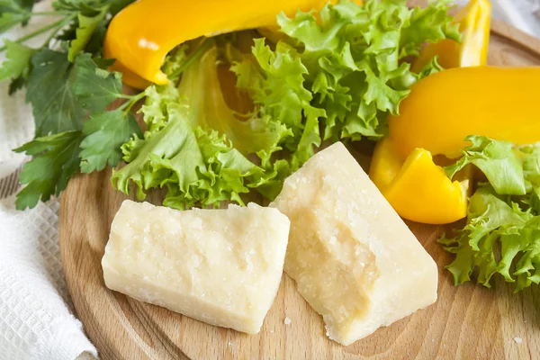 Parmigiano-Käse um frischen gelben Pfeffer Salat Blätter Petersilie auf Holzbrett und Serviette Hintergrund — Stockfoto