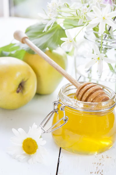 Appel, honing en bloemen op licht houten tafel — Stockfoto