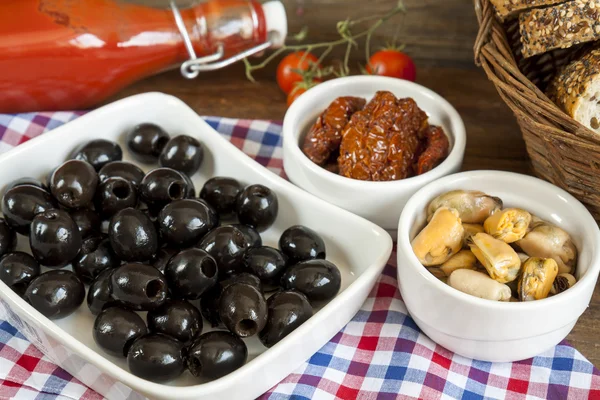 Black olives, sun dried tomatoes and mussels in ceramic bowls