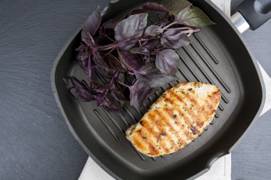 Izgara tavuk göğsü biftek üzerinde teflon tava gri mor fesleğen ile