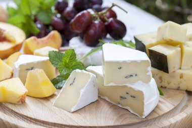 Farklı lezzetli peynir ve meyve ahşap yuvarlak tahta üzerinde