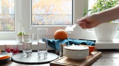 Gerçek bir kadın, pencerenin yanında buzlu mavi cin tonik kokteyli hazırlıyor. Güneşli sonbaharda pencerenin yanındaki masaya buz koymak.