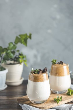 Dalgona köpüklü kahve ile iki bardak Kore kahvesi kekik ve koyu çikolatayla süslenmiş kahve köpüklü latte espresso. Koyu tahta masa yüzeyi