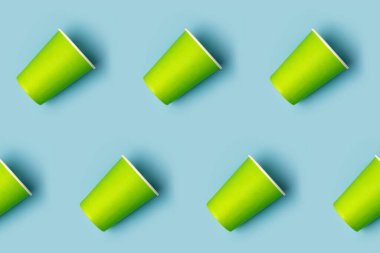 Yeşil kağıt bardakların deseni mavi arka planda çapraz dizilmiş. Doğum günü partisi soyut moda bebek partisi konsepti. Minimalist stil