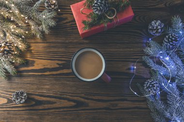 Noel arkaplanda bir fincan kakao ve bayram bayramını kutlamak için hazırlanan koyu ahşap masa üzerine sarılı hediye paketi var. Boşluğu kopyala.