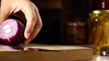 Kadın elleri mutfakta soğan kesiyor. Kırmızı soğanlı Makro atış. Kadın tahtadan soğan kesiyor..