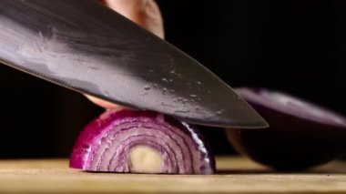 Kadın elleri mutfakta soğan kesiyor. Kırmızı soğanlı Makro atış. Kadın tahtadan soğan kesiyor..