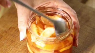 Elinde kaşık olan kadın cam kavanozdan elma reçeli alıyor. Videoyu kapat.