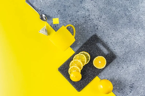 stock image Creative tea food background of Ultimate Gray and Illuminating trending color. Tea, lemon, cup and spoon on gray and yellow table surface, top view.