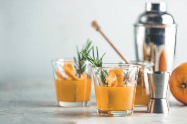  Biberiye şurubu ya da ev yapımı viski kokteyli. Portakal ve biberiyeli. Portakal kabuğunu süsleyin. Hafif beton yüzey