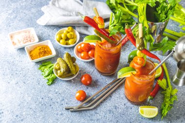 Kerevizli domates suyu, baharat, tuz ve buzlu porsiyon bardakta fotokopi alanı. Bloody Mary kokteyli. Alkolik içecek ve gri beton masa yüzeyindeki malzemeler.