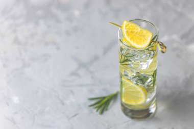 Açık gri arka planda buzlu cam kadehlerle limonlu limonlu içecek. Yaz taze limonlu kokteyl biberiyeli, seçici odaklı. 