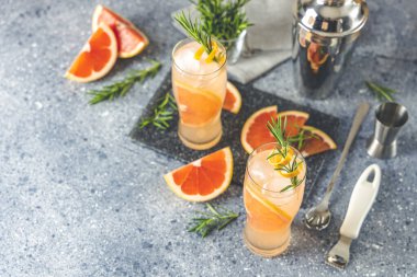 İki bardak Paloma kokteyli, tekila taze greyfurt suyu ve biberiye. Gri beton yüzey.