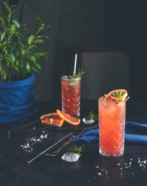 Pembe Greyfurt Mezcal Paloma Kokteyli viski bardağında. Gerçek evdeki masada su damlaları var. Yeni yaşam konsepti karantina. Yaklaş, alanın sığ derinliği, koyu arkaplan.