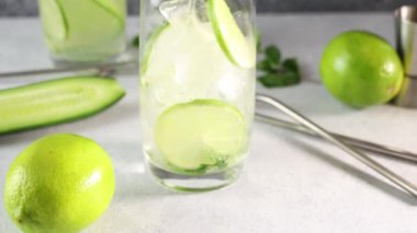 Mojito kokteyli ya da nane, salatalık ve kireç karışımını gri beton yüzey zeminine dökmek. Kamera cam boyunca hareket ediyor.