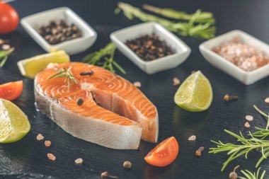 Tahtada çiğ somon bifteği ve tuz, biber, limon, karanfil ve biberiye. Çiğ somon balığı. Somon balığı pişirmek, deniz mahsulleri. Sağlıklı gıda konsepti. Somon ve baharat.