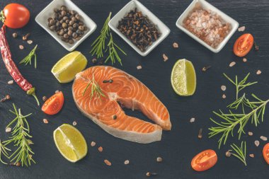 Tahtada çiğ somon bifteği ve tuz, biber, limon, karanfil ve biberiye. Çiğ somon balığı. Somon balığı pişirmek, deniz mahsulleri. Sağlıklı gıda konsepti. Somon ve baharat.