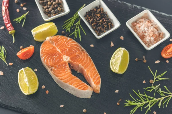 Tahtada çiğ somon bifteği ve tuz, biber, limon, karanfil ve biberiye. Çiğ somon balığı. Somon balığı pişirmek, deniz mahsulleri. Sağlıklı gıda konsepti. Somon ve baharat.