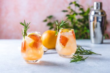 Tekila kokteyli ya da greyfurt suyu katılmış soğuk limonata. Moda pastel arka planında taze biberiye filizi aromasıyla renklendirilmiş..