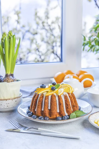 Böğürtlenli turuncu kek. Etrafı meyvelerle çevrili. Çiçek ve çatal bıçak seti pencere kenarında. Aile kahvaltısı kavramı