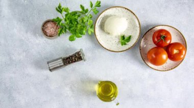 Dilimlenmiş taze domatesli Caprese salatası, mozzarella peyniri ve fesleğen açık gri masa yüzeyinde beyaz bir tabakta servis edilir. Geleneksel İtalyan yemekleri. Hareketi durdur