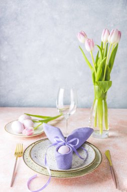 Çatal bıçaklı Paskalya sofrası, pembe lale çiçekleri ve pembe masadaki paskalya yumurtaları..